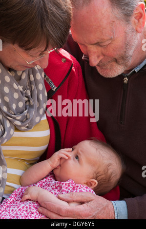 Grandparents holding and cuddling their little granddaughter Stock Photo