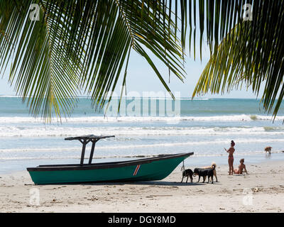 Boat, Costa Rican women and dogs on the beach, Playa Samara, Nicoya Peninsula, Costa Rica, Central America Stock Photo