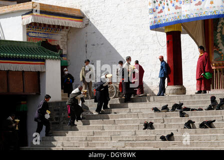 Tibetan believers and pilgrims with large butter lamps climbing the stairs in front of the Assembly Hall, Tibetan: Dukhang Stock Photo