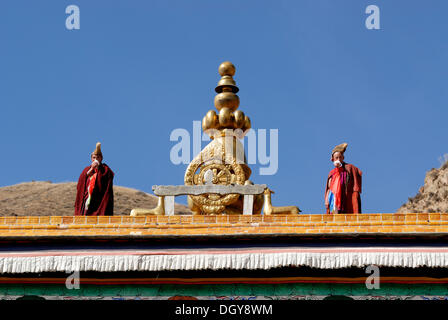 Tibetan monks wearing robes and yellow hats of the Gelug Order or Yellow Hat Sect standing on the roof of the Assembly Hall Stock Photo