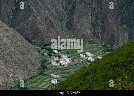 Aerial view of the Tibetan architecture of a small village, houses in a steep canyon surrounded by terraced fields for Stock Photo