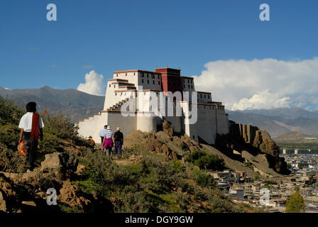 Pilgrims and a group of tourists in front of the reconstructed Shigatse Dzong Fortress, with the historic town centre of the Stock Photo