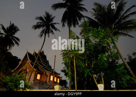 Palm trees and the Buddhist temple of Wat Ho Pha Bang on the grounds of the Laotian Royal Palace in Luang Prabang in the early Stock Photo