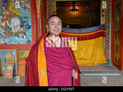 Tibetan Buddhism, Tibetan monk in a red monk's robe in the monastery building, traditional architectural style Stock Photo