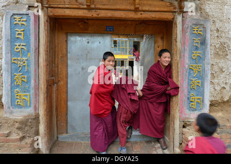 Two young novice monks, students standing in front of the entrance to a Buddhist monastery school, monastery building in the Stock Photo