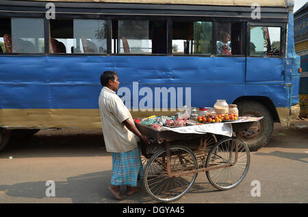 Street scene, Indian man is pushing a simple food art with goods for sale to a coach outside the ruins of the ancient University Stock Photo