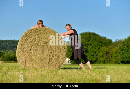 Heavily pregnant women, nine months, and girl, six years, lying on a straw bale Stock Photo