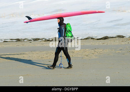 Surfer carrying surfboard on his head, ski surfing, beach of Unnstad, Island of Vestvågøya, Lofoten Islands, Northern Norway Stock Photo