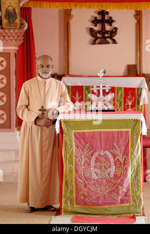Catholic priest in front of the cross of the St. Thomas Christians, Mar Thoma Sleeha monastery, Thiruvalla, Kerala, South India Stock Photo