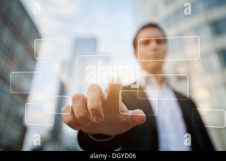 hand pushing on a touch screen interface on business buildings background Stock Photo