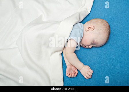 Sleeping baby on bed under blanket Stock Photo