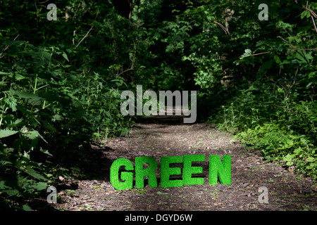 Green turf block letters spelling out GREEN on a footpath in nature Stock Photo