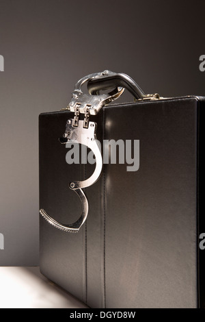 A briefcase with handcuffs attached to the handle Stock Photo