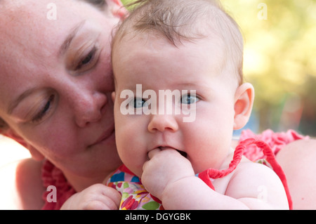 Close up of mother cuddling her baby girl outside in the garden Stock Photo