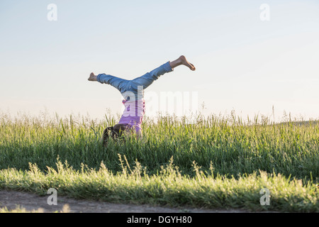 A young girl doing a handstand with her legs apart in a split Stock Photo