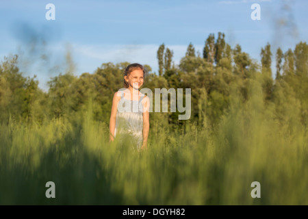 A young cheerful girl standing in a field looking at the view Stock Photo