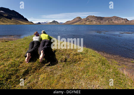 Young couple lying on a meadow, Lake Álftavatn, Iceland, Europe Stock Photo