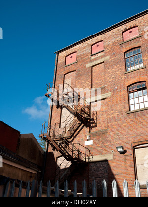 Fire escape from bricked up doorway to ground level on an old warehouse. Oldham, Greater Manchester, UK. Stock Photo