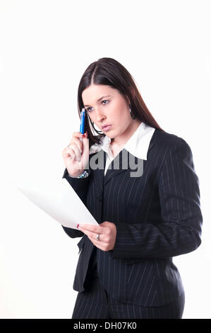 Businesswoman holding a pen and a letter, pondering Stock Photo
