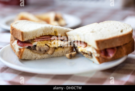A halved bacon, egg and mushroom sandwich on a plate, London, England, UK. Stock Photo