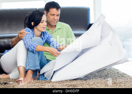 Hispanic couple examining blueprints in living room Stock Photo
