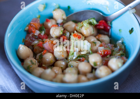 Chickpea salad with herbs and peppers in blue bowl, close up