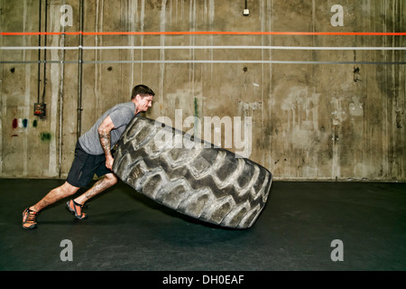 Caucasian man lifting large tire in gym Stock Photo
