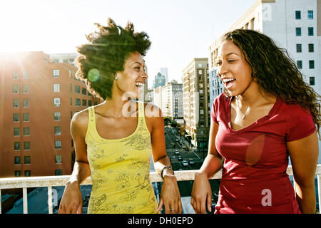 Mixed race women smiling on urban rooftop Stock Photo