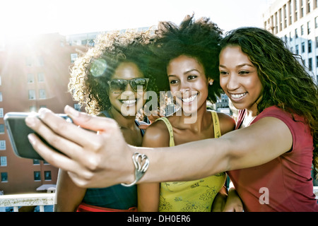 Mixed race women taking self-portrait on urban rooftop Stock Photo