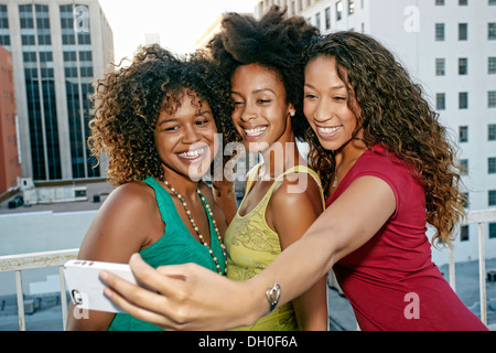 Mixed race women taking self-portrait on urban rooftop Stock Photo