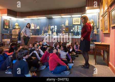 class of schoolchildren listening to teacher on field trip to Carnavalet Museum, Paris, France Stock Photo