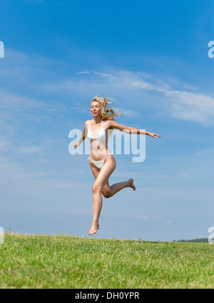 The happy young woman jumps in the field Stock Photo