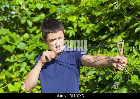 Boy with a slingshot near the bush Stock Photo