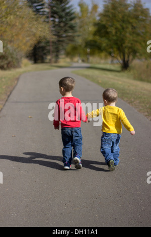 Two beautiful brothers holding hands enjoying life walking down a path Stock Photo