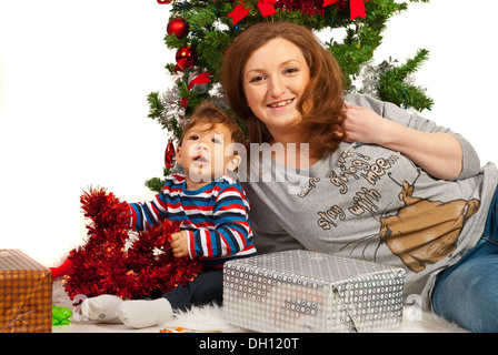 Happy mother with her son sitting under Christmas tree Stock Photo