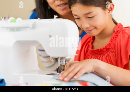 Mother teaching girl to use sewing machine Stock Photo