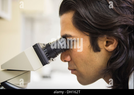 Indian scientist using microscope in laboratory Stock Photo