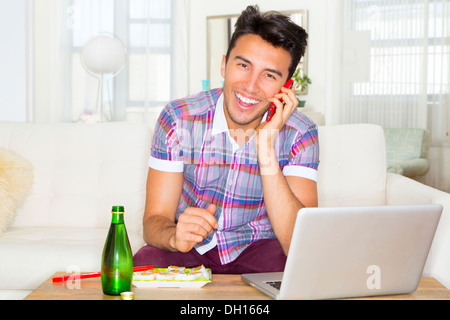 Mixed race teenager using laptop and cell phone Stock Photo