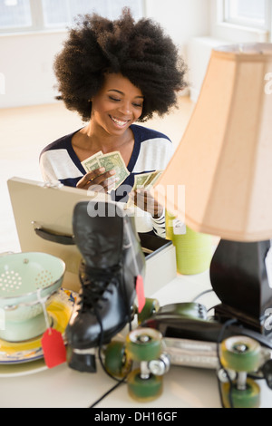 Mixed race woman counting money from yard sale Stock Photo