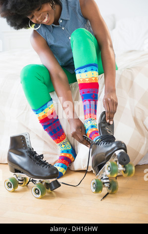 Mixed race woman putting on roller skates Stock Photo