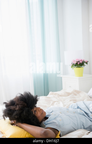 Mixed race woman laying on bed Stock Photo