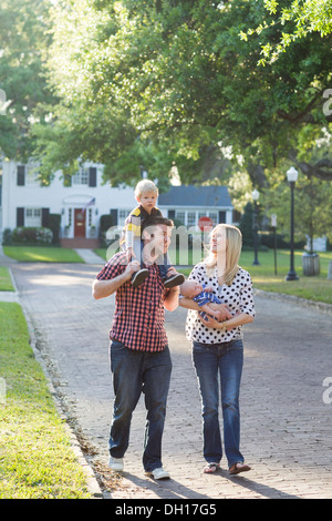 Caucasian family walking along neighborhood street Stock Photo