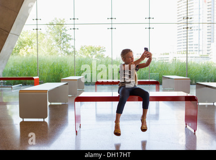 Caucasian girl taking self-portrait in lobby Stock Photo