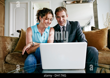 Caucasian couple using laptop in living room Stock Photo
