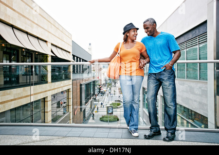 Couple standing on sky bridge at shopping mall Stock Photo