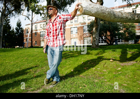 Man leaning against tree branch in park Stock Photo