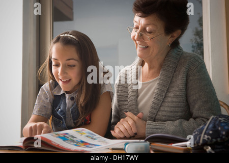 Older Hispanic woman reading with granddaughter Stock Photo