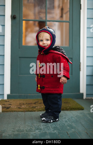 Caucasian boy wearing winter coat on porch Stock Photo