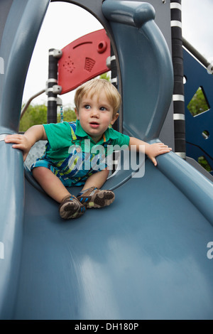 Caucasian boy playing on slide Stock Photo