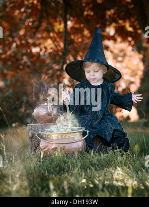 Little halloween witch , boiling a potion, outdoors in the woods Stock Photo